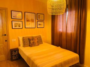 a bedroom with a bed with yellow walls and a chandelier at Casa del palmar suite in Valencia