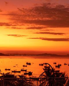 a group of boats in the water at sunset at Hotel Maricá in Penha