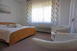a bedroom with a bed and a chair and a window at Ferienwohnung Wiesengrund in Bad Endbach