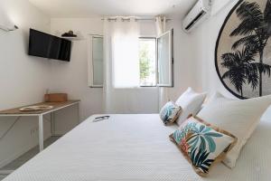a bedroom with a white bed with pillows and a desk at Paradize- Plage & 3Piscines - Anse Marcel in Anse Marcel 