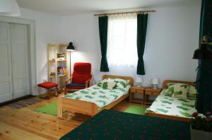 a bedroom with two beds and a red chair at Chatka na Roztoczu in Bondyrz