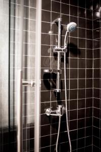 a shower in a bathroom with black tiles at C U Inn Bangkok in Bangkok +32 photos