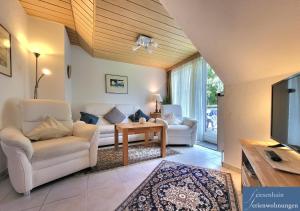 a living room with white furniture and a tv at Friesenhain Ferienwohnungen in Sankt Peter-Ording