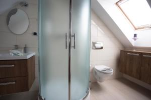 een badkamer met een glazen douche en een toilet bij Apartament Tyniecki in Darłowo