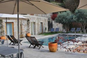 um pátio com cadeiras, um guarda-sol e uma piscina em Casas Da Lapa, Nature & Spa Hotel em Seia