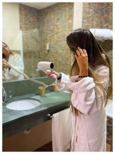 a little girl is blow drying her hair in a bathroom at Hotel Albaida Nature in Mazagón