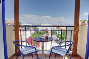 a table with two chairs and a bottle of wine on a balcony at STUDIOS ATHENA in Megalochori