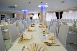 un salón de banquetes con mesas blancas y sillas blancas en Hotel Insteia, en Polla