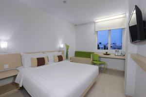 Un dormitorio con una gran cama blanca y una ventana en Algoritma Hotel, en Palembang