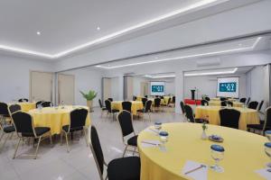 una sala de conferencias con mesas y sillas amarillas en Algoritma Hotel, en Palembang
