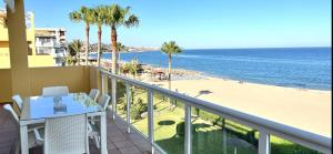 balcón con mesa y sillas y playa en BEACHFRONT APARTMENT In MIJAS COSTA, en Mijas Costa