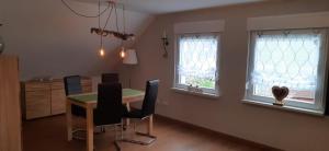 a dining room with a table and chairs and two windows at Ferienwohnung Schilling in Hameln