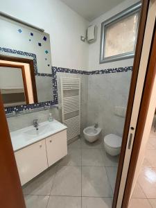 een badkamer met een wastafel, een toilet en een spiegel bij Casa Milano - Sottomarina in Sottomarina