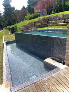 een zwembad in een tuin met een stenen muur bij El Refugi de la Torre Espinalbet in Castellar del Riu