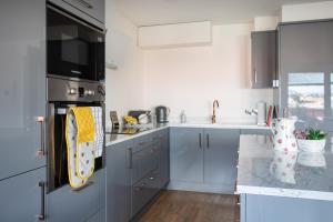 a kitchen with gray cabinets and a sink at New Lisburn Road Apartment - Free Parking in Belfast