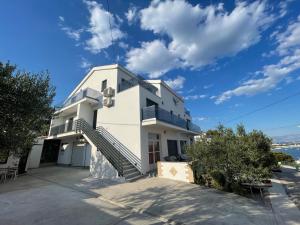 a white house with stairs and a blue sky at Eva Apartment 2 in Trogir