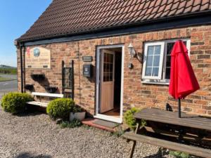 a brick house with a red umbrella and a bench at Yarm Cottages Sleeping 6 Next to Fox Covert Pub in Kirk Leavington