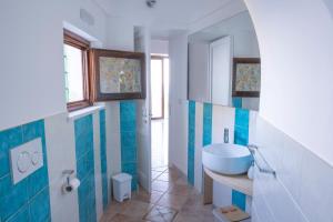 e bagno con lavabo e piastrelle bianche e blu. di Emerald's Resort - Filomena a Conca dei Marini