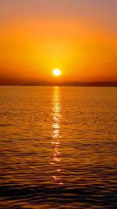 a sunset over a body of water with the sun setting at Golden Sunset Beach Apartment in Skala Kallirakhis