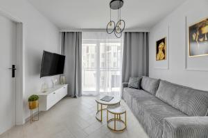 a living room with a couch and a tv at Apartamenty PIAMOLA Bursztynowe Osiedle Jantar in Jantar