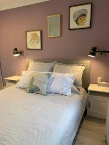 uma cama com lençóis brancos e almofadas num quarto em Ambiance by the Falls Cozy Suite em Cataratas do Niágara