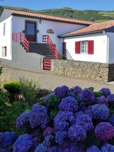 una casa con flores púrpuras delante de ella en Casa da Travessa en Santa Cruz das Flores