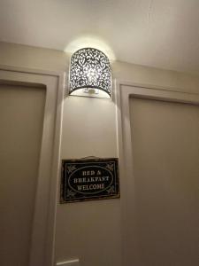 a sign on a wall with a light above a door at Le cocon jaune - Studio en hyper centre in Lamballe