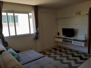 Una sala de estar con un sofá y un televisor. en Jockey Family Chamonix 3, en Vila Velha