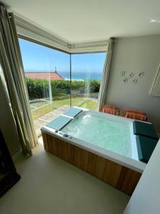 uma banheira de hidromassagem num quarto com uma grande janela em Casa do Cruceiro surfing Costa da Morte em Cayón