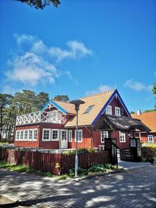 a red house with a fence in front of it at Nidos Seklyčia in Nida