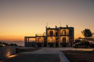 a house with a sunset in the background at ErMoJo Luxury Apartments in Metókhion Patriotikón