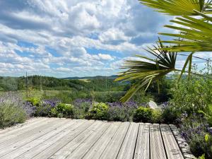 a wooden deck in a garden with purple flowers at LuxApart Eifel mit privater Outdoor-Sauna in Harscheid