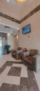 a living room with two couches and a tv on the wall at فندق ربوة الصفوة 8 - Rabwah Al Safwa Hotel 8 in Al Madinah