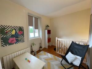 a room with a crib and a table and a chair at Le cocon jaune - Studio en hyper centre in Lamballe