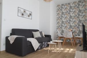 a living room with a black couch and a table at Le Zen by EasyEscale in Romilly-sur-Seine