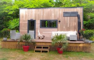 uma pequena casa sentada num deque com plantas em Tiny house chez Caroline em Gaillan-en-Médoc