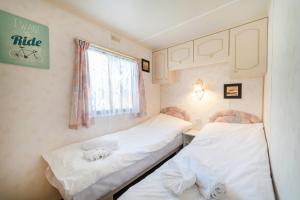 2 łóżka w małym pokoju z oknem w obiekcie Domek 112 w Jastarni