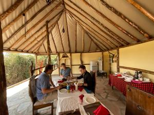 three men sitting at a table in a tent at Olaloi Mara Camp in Masai Mara