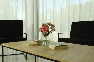 a vase of flowers sitting on a table with two chairs at Graphica Black Sea in Shekhvetili