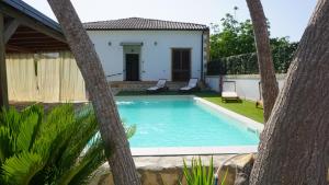 a swimming pool with palm trees in front of a house at Country house relais Nonna Rosa Rosolini (SR) in Siracusa