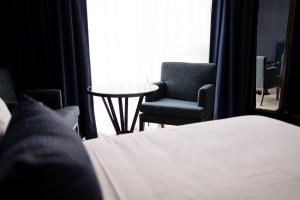 Cambria Hotel Boston Somerville في سومرفيل: غرفة نوم بسرير وكرسيين وطاولة