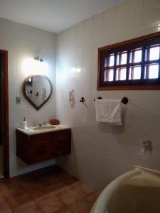 a bathroom with a sink and a tub and a mirror at Casa vista lago vitoria regia in Holambra