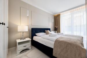 a bedroom with a large bed with a lamp and a window at Apartamenty Prestige Mielno-Uniescie in Unieście +121 photos