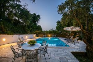 una piscina con sedie, tavolo e ombrellone di Villa Scheria a Benitses