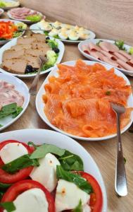 una mesa cubierta con platos de comida con tomates y carne en Tasarz Spa Ośrodek Wczasowy en Rewal