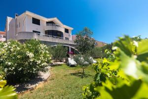 una grande casa bianca con un cortile con cespugli di Villa Paradiso a Punat