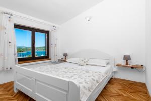 una camera da letto bianca con un letto grande e una finestra di Villa Paradiso a Punat