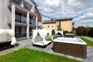 un patio con bañera de hidromasaje y sillas y un edificio en Apartamenty Prestige Mielno-Uniescie, en Unieście
