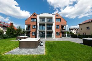 a large brick house with a lawn in front of it at Apartamenty Prestige Mielno-Uniescie in Unieście