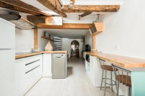 una cocina con armarios blancos y techos de madera. en La Aduana de Sol, en Madrid